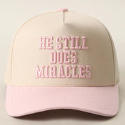 Light Pink He Still Does Miracles Hat — color: cream with a black brim and embroidered "HE STILL DOES MIRACLES" across