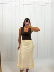 AI-assisted styled photo of Yellow Satin Midi Skirt on boutique owner, soft original-room lighting approved September 21 2026
